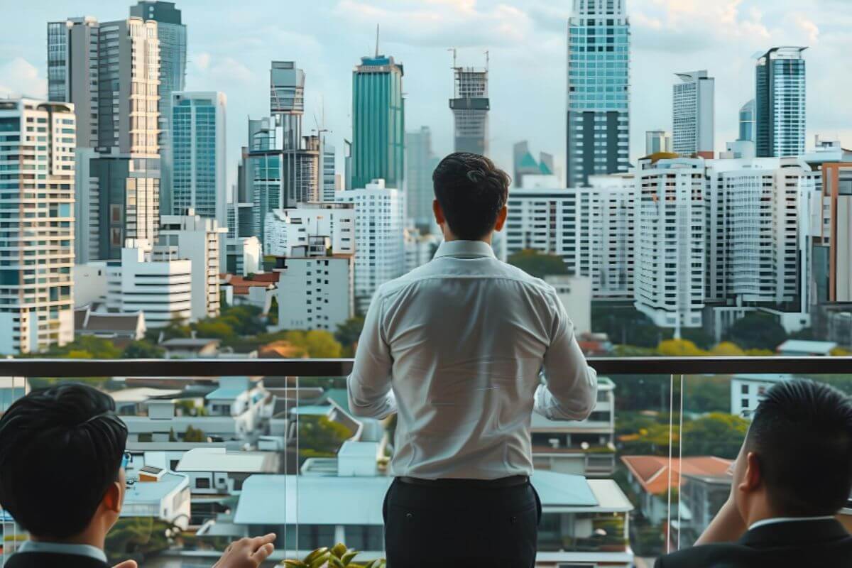 A person thoughtfully considering a property purchase with developers seated in the background, symbolizing evaluation and decision-making in real estate investment.