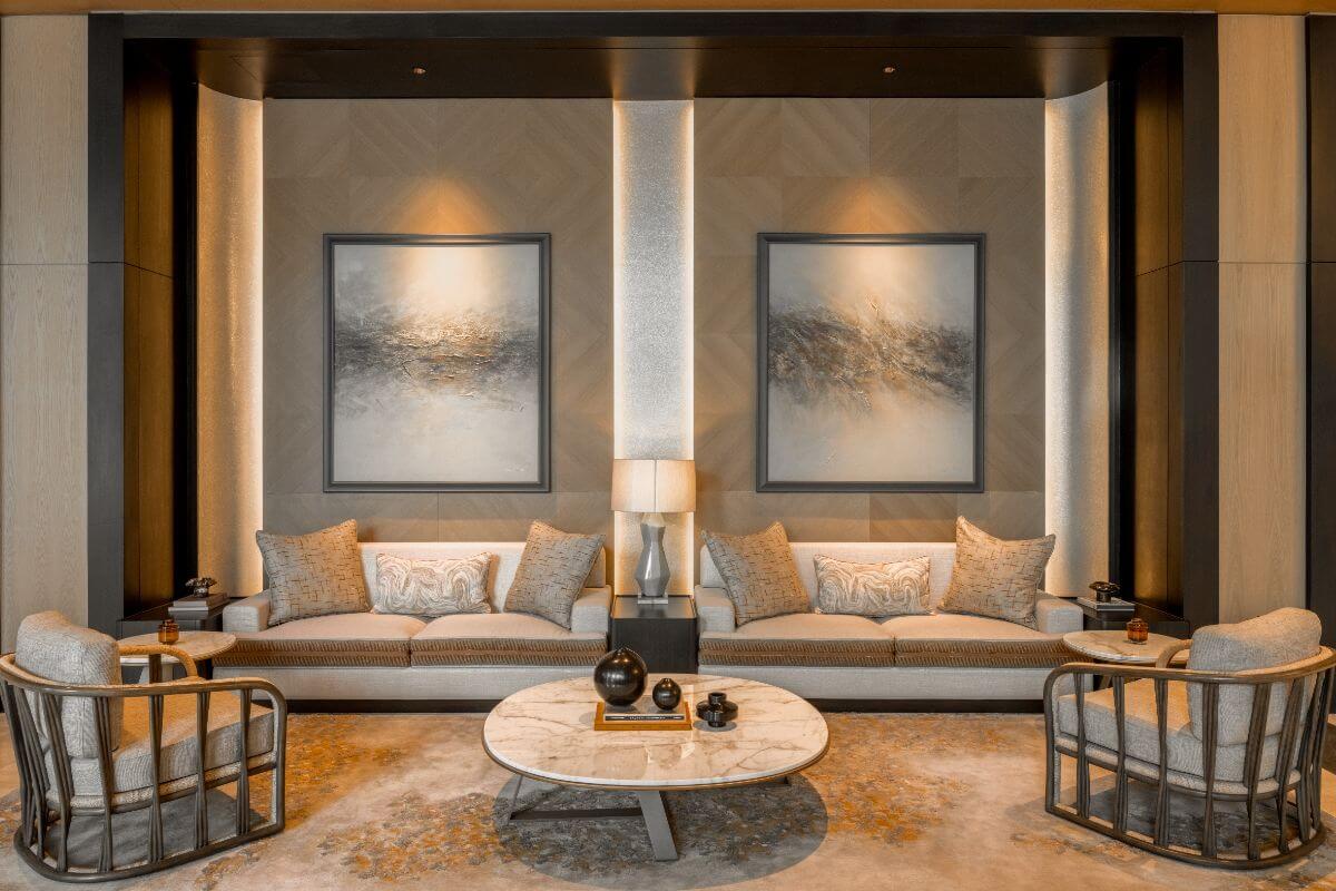 Sophisticated seating area with twin sofas, marble table, artwork, and warm ambient lighting
