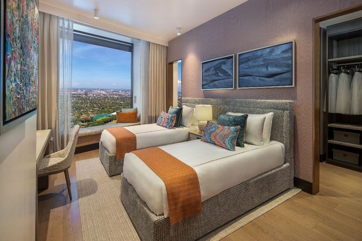 Elegant twin bedroom with floor-to-ceiling city views inside a luxury condominium at Aurelia Residences