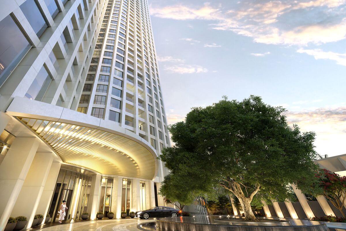 Exterior entrance of Aurelia Residences with an illuminated canopy, landscaped grounds, and a mature tree