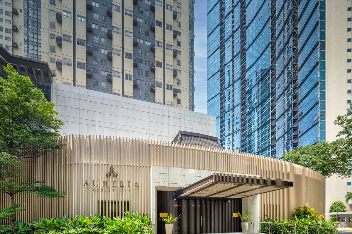 Exterior entrance of Aurelia Residences surrounded by landscaped greenery and modern high-rise buildings